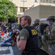 A DEA agent confers with several soldiers as protesters march to the White House on June 2.